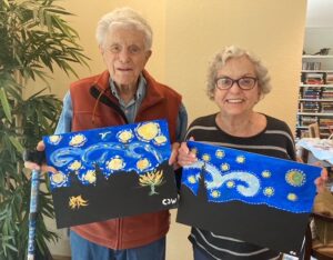 Two seniors holding up their paintings that are their versions of a starry night by Van Gogh