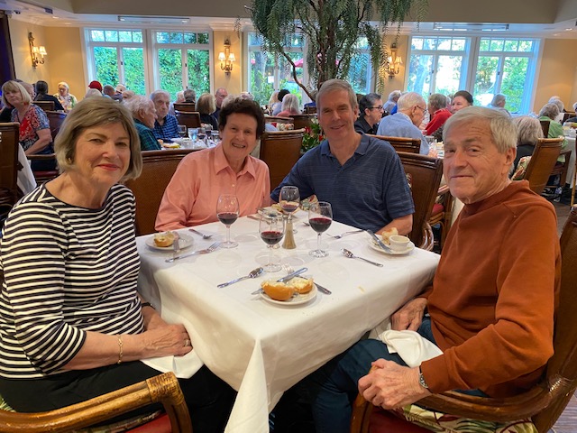 People posing for Photograph at a table about to have dinner with wine glasses on the table and bread