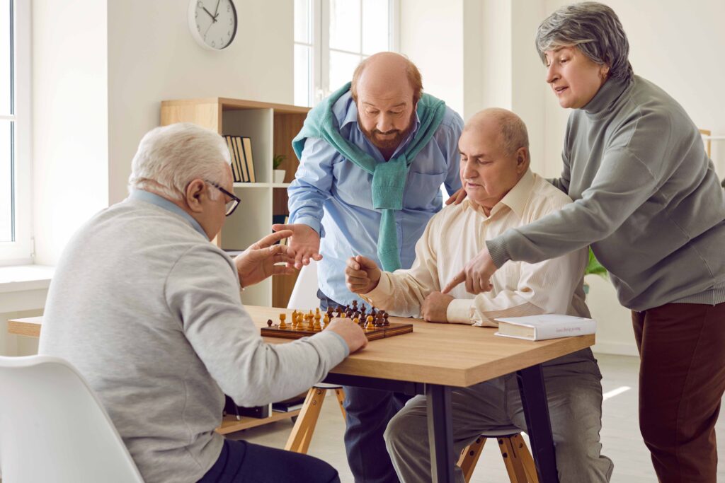 Group of seniors playing board games in retirement home. Several old people playing chess to stimulate new neural connections, prevent cognitive disorders and battle dementia brain cells damage